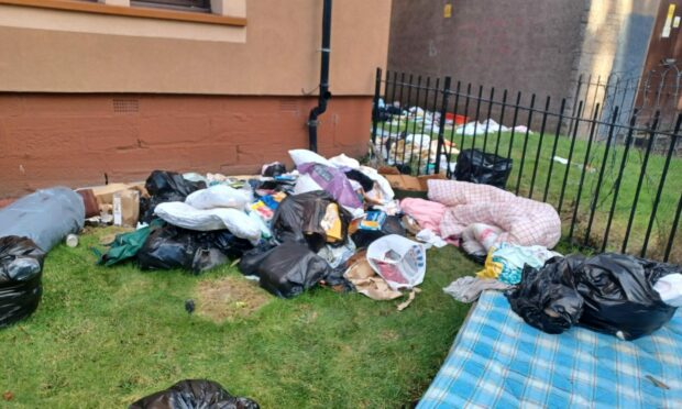 Rubbish left dumped in a communal garden area on Dens Road, Dundee.