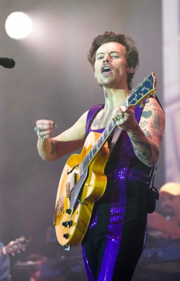 Harry Styles on stage in purple glittery jumpsuit