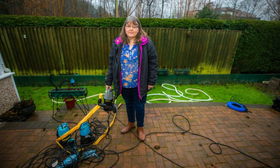 Janice Haig standing in Perth garden next to equipment she uses to pump water of her home