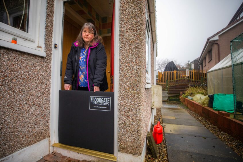 Janice Haig standing behind floodgate at the door of her home in the Craigie area of Perth