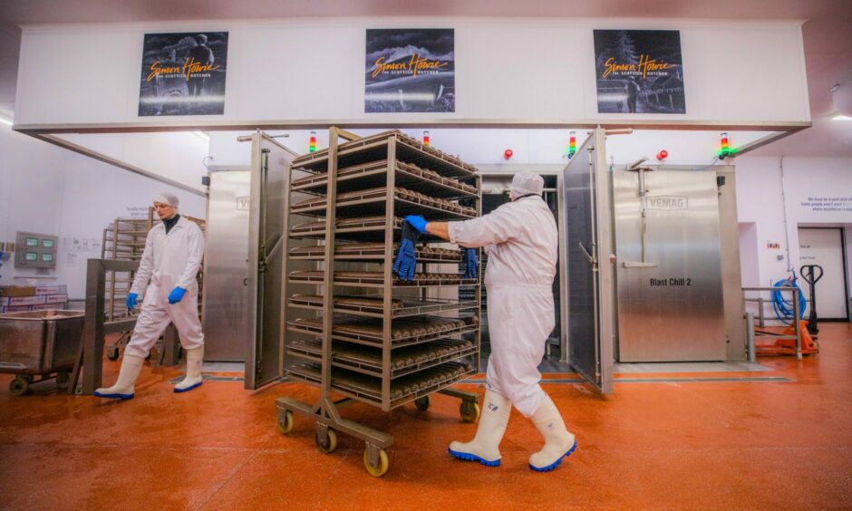 Workers pushing trolley containing trays of haggis in Simon Howie factory, Dunning.
