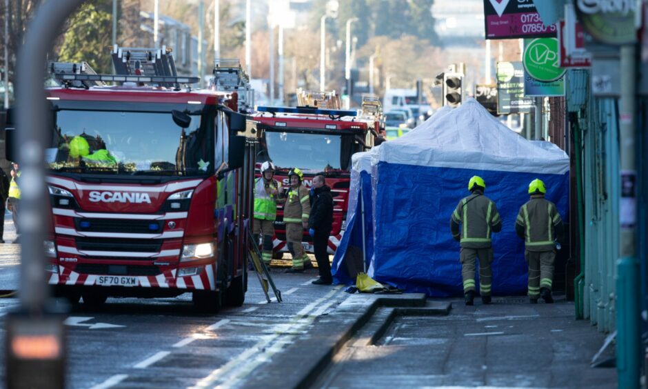 Fire engines remain on County Place alongside a blue tent erect by investigators.