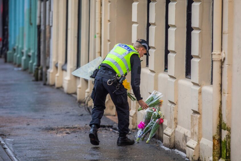 police officer lays flowers at the scene of the New County Hotel fire.