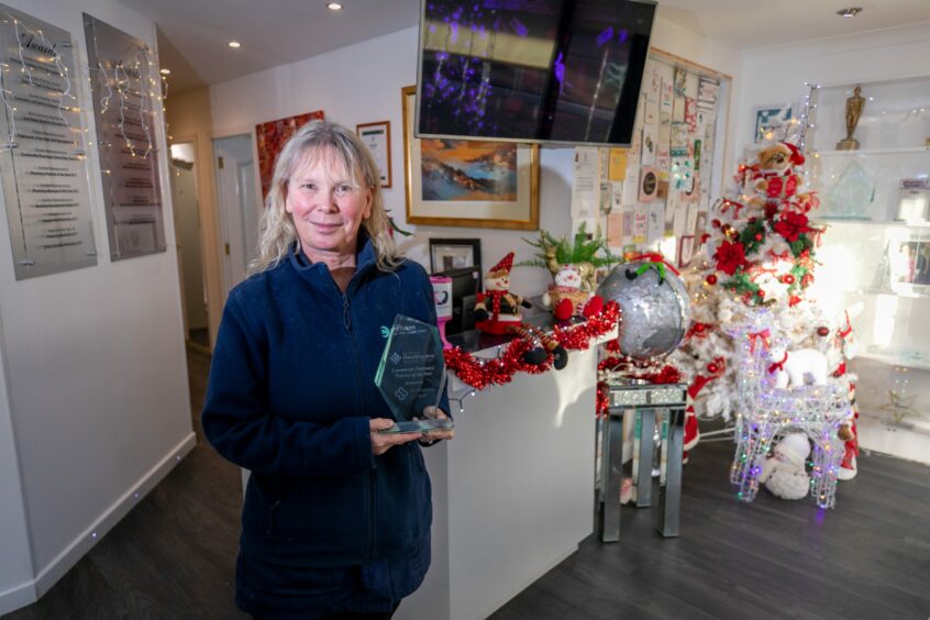 Bernadette in the reception of Cadham Clnic in Glenrothes, with her Community Pharmacy of the Year award.