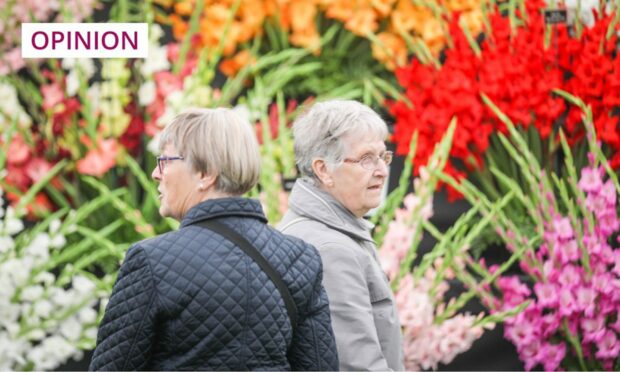 two women next to a colourful display of gladioli.