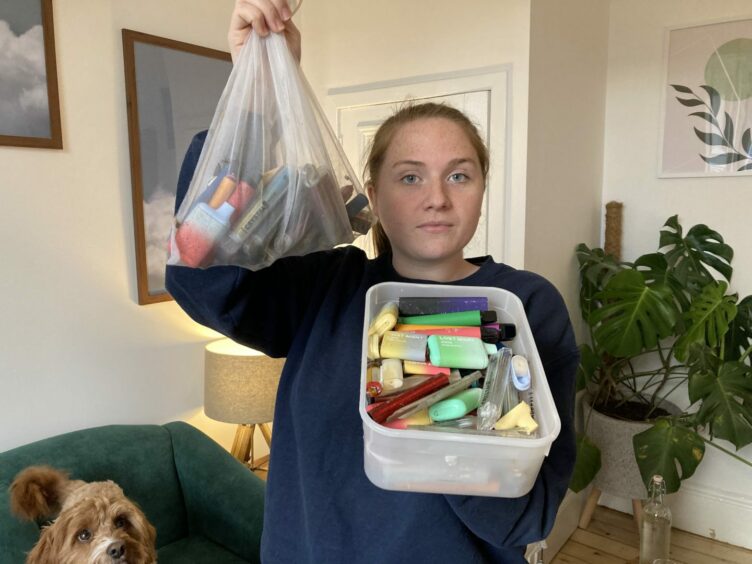 Dundee environmental campaigner Laura Young holding up a box and a bag filled with disposable vapes picked up from streets across the city.