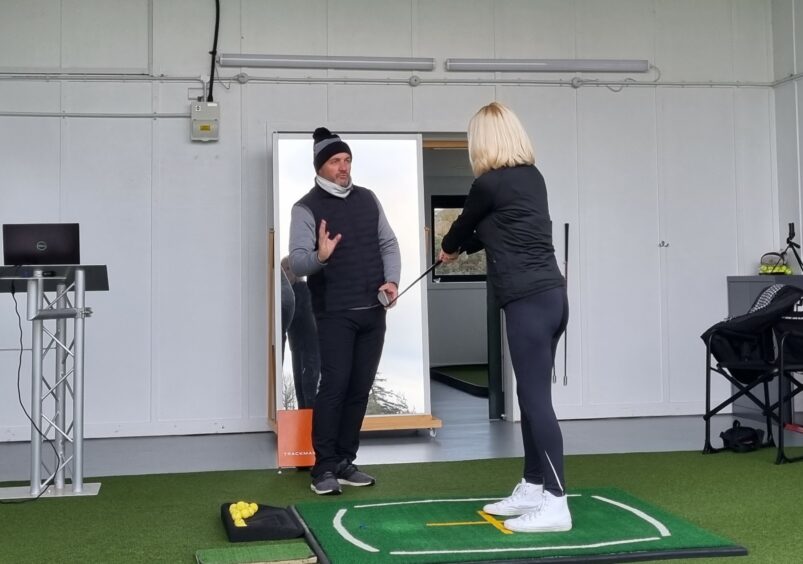 A photo of golf pro Stuart Syme showing Laura how to start playing golf