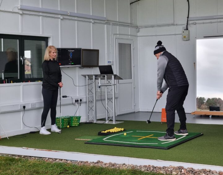 A photo of golf pro Stuart Syme showing golf beginner Laura how to play
