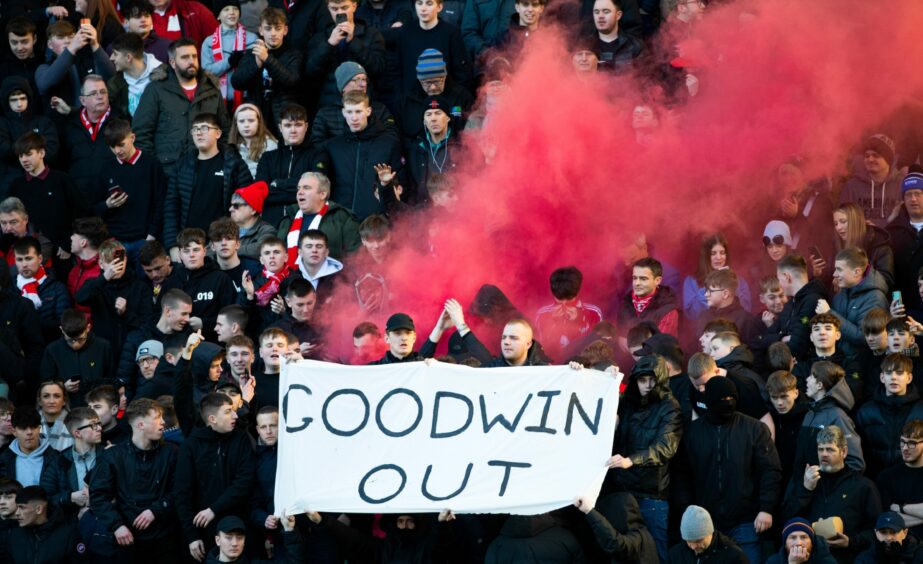 Aberdeen supporters holding a large banner which reads 'Goodwin out'.