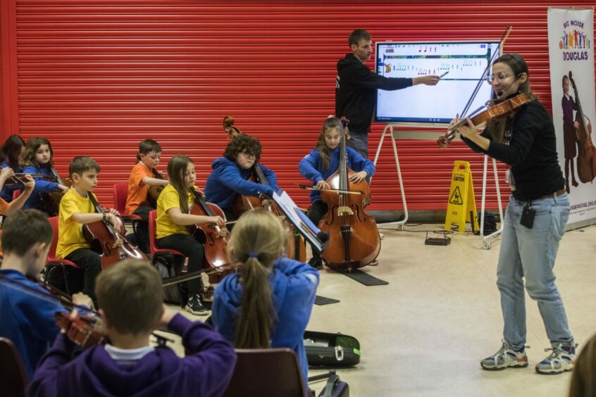group of children playing musical instruments at a rehearsal session.