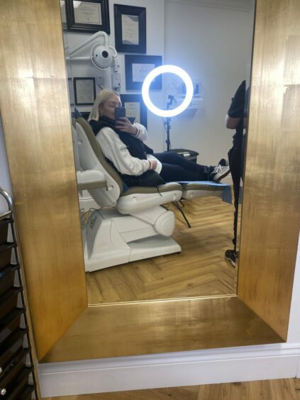 Lynne Hoggan taking a selfie in a chair at a beauty clinic