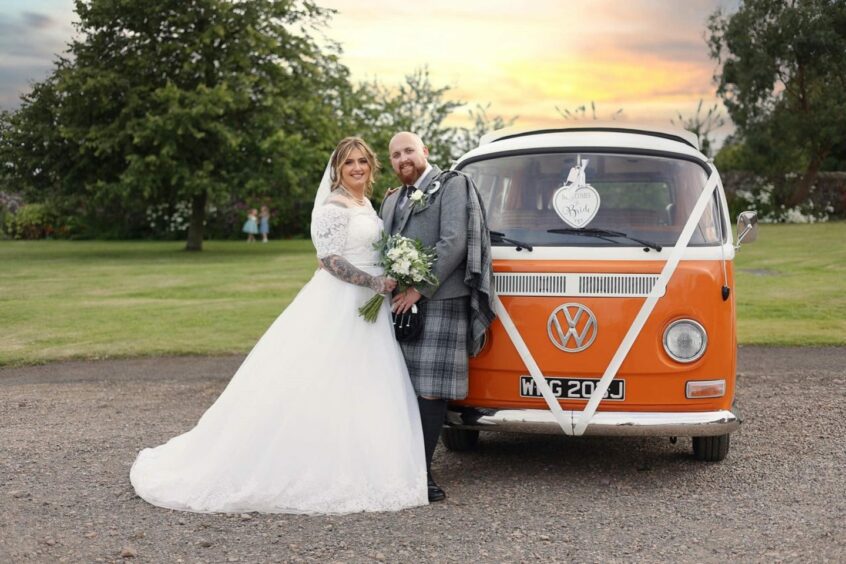 Married couple in front of camper van with florals near Fife.