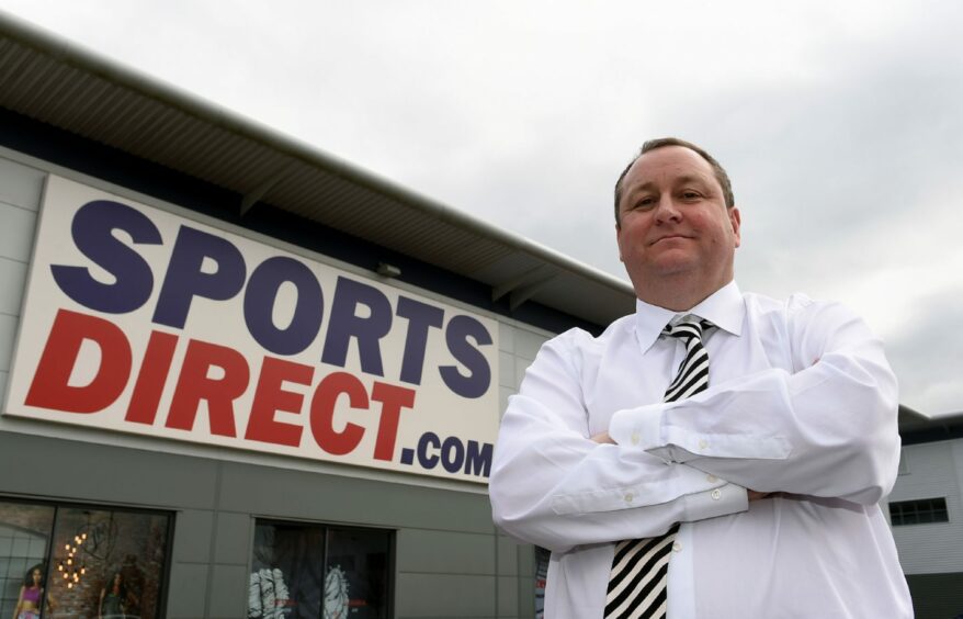 Mike Ashley, arms folded, outside a Sports Direct store.
