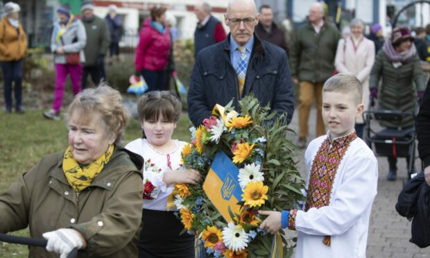 Ukrainian children Yeva Berehovenko (left) and Sasha Protsenko carry a wreath during the ceremony. Image: Phil Hannah.