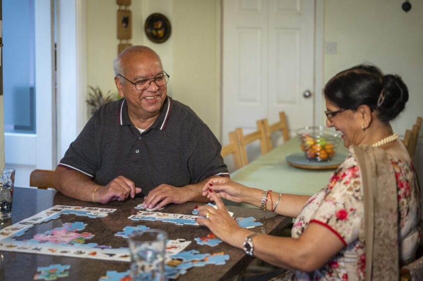 an elderly man and an elderly woman solve a puzzle together