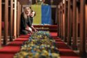 Artists Mary-Ann Orr and Lucy Nychai with a carpet of paper sunflowers laid out at Auchmithie church. Image: Gareth Jennings/DC Thomson