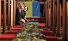 Artists Mary-Ann Orr and Lucy Nychai with a carpet of paper sunflowers laid out at Auchmithie church. Image: Gareth Jennings/DC Thomson