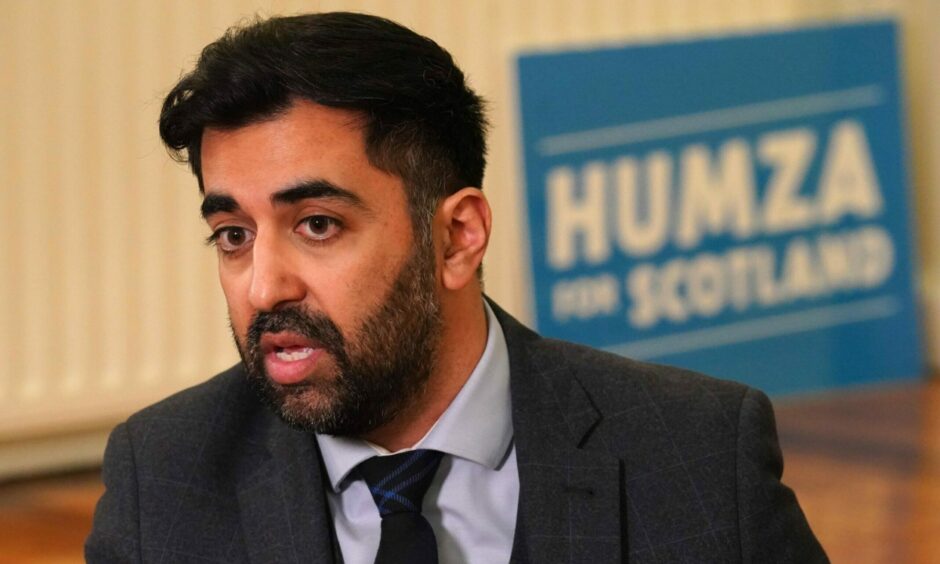 Humza Yousaf in front of a Humza for Scotland poster.
