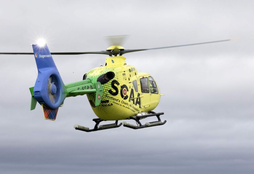 Yellow Scotland's Charity Air Ambulance aircraft in a grey sky.