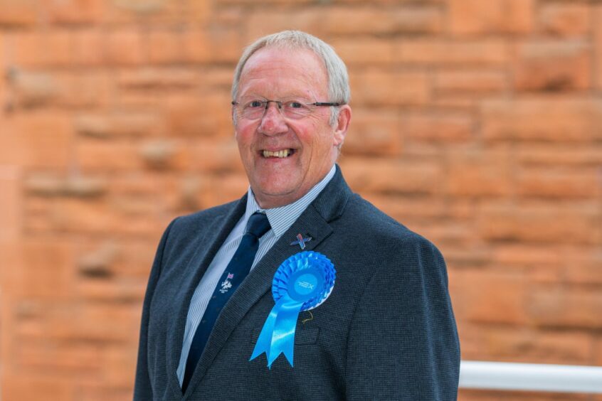 Ian James smiling wearing blue Conservative party rosette