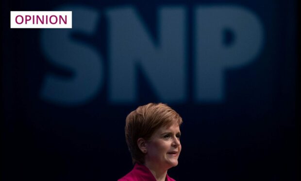 Nicola Sturgeon under a large SNP logo.