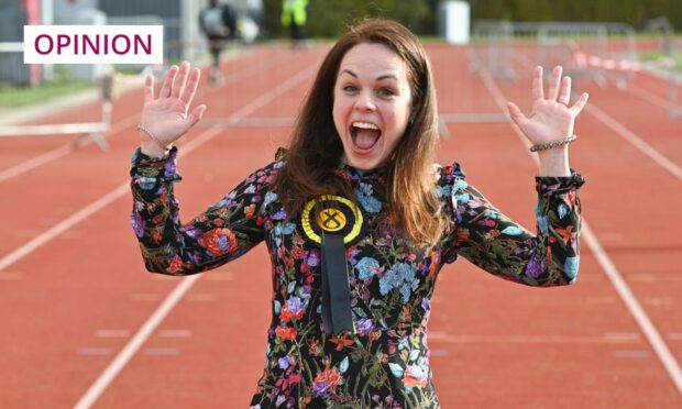 Kate Forbes hands aloft, wearing a SNP rosette