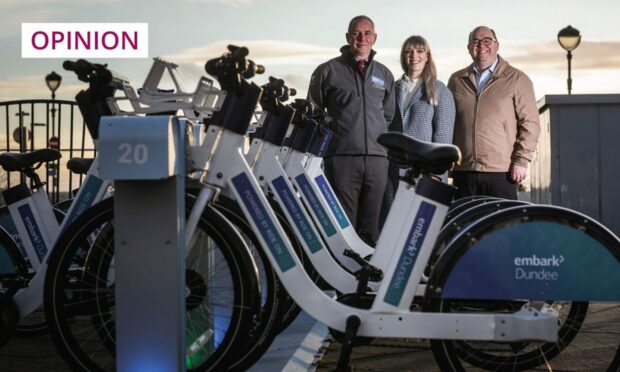 Three people standing next to a row of e-bikes at Dundee Waterfront.