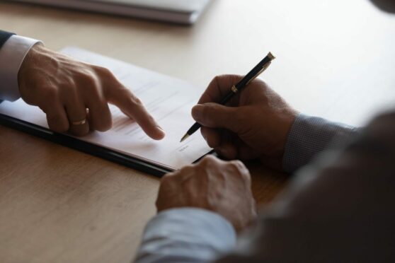 Two people signing a will. If you've not set up your will, a free will writing service in Scotland will help you.