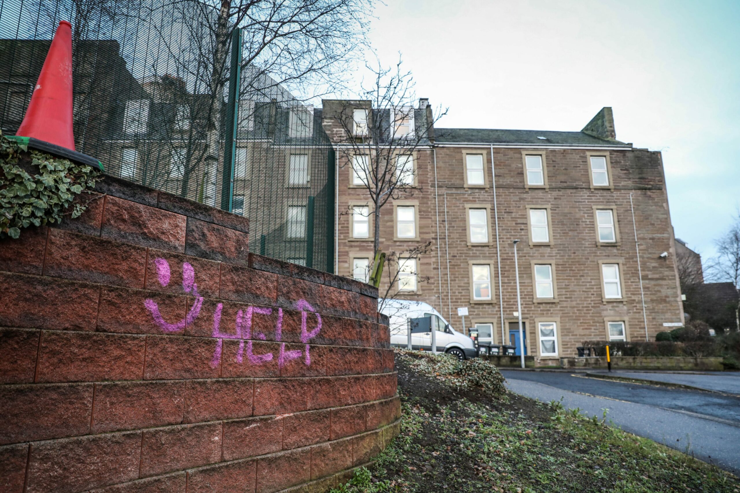 flats in Dundee with a spraypainted wall that reads 'help'