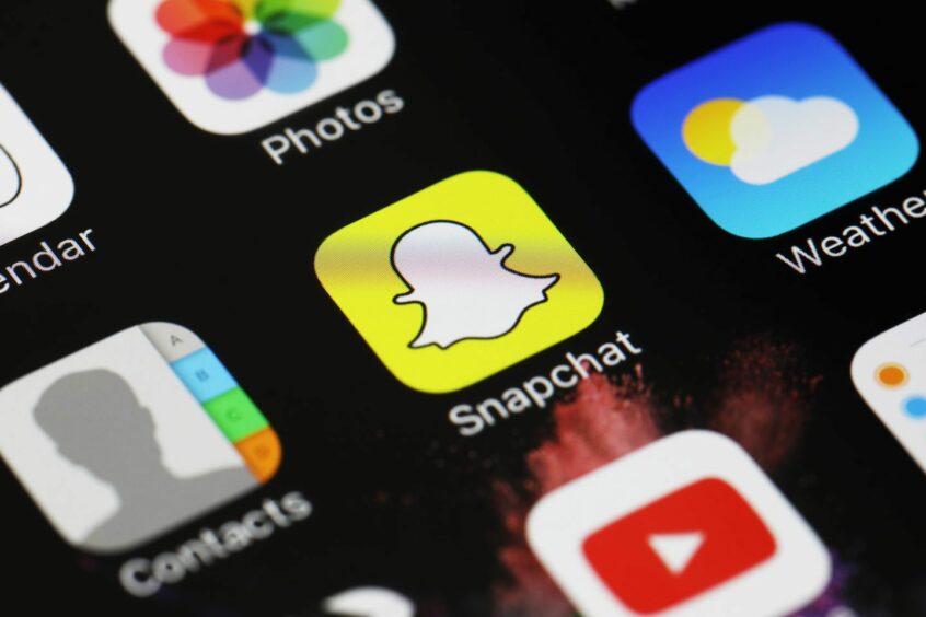Phone screen showing Snapchat logo.