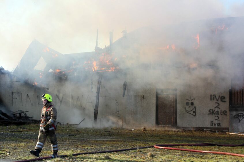 Fire fighter walking in front of burning hotel