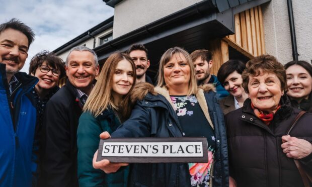Fiona Scott, Steven’s wife, holding the street sign with members of the Scott family joined by Alan Nairn, Chair of Caledonia Housing Association (CHA). Image: Supplied by aledonia Housing Association.