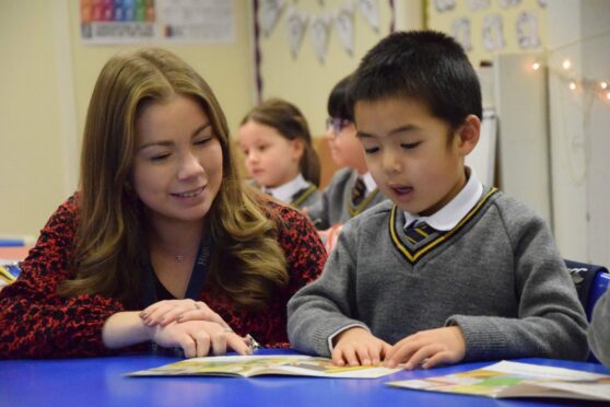 A teacher helps a pupil as he makes the P1 transition from nursery