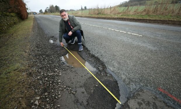 Stuart Pirie measuring the pothole near Craichie in Angus. Image Gareth Jennings/DC Thomson
