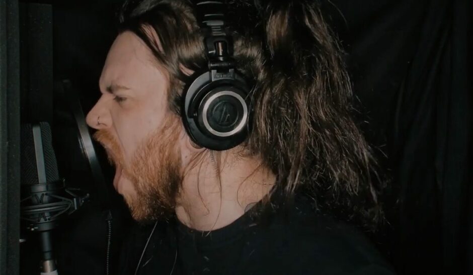 Lewis Brodies in headphones singing into a microphone.
