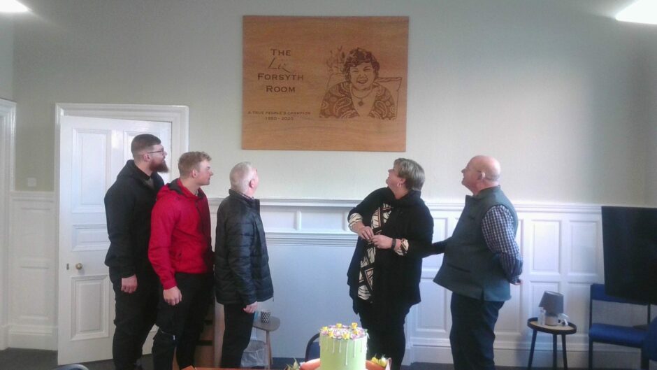 The family of Liz Forsyth admire the Voluntary Action Angus boardroom portrait.