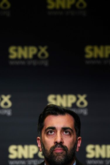 Humza Yousaf in front of SNP signs