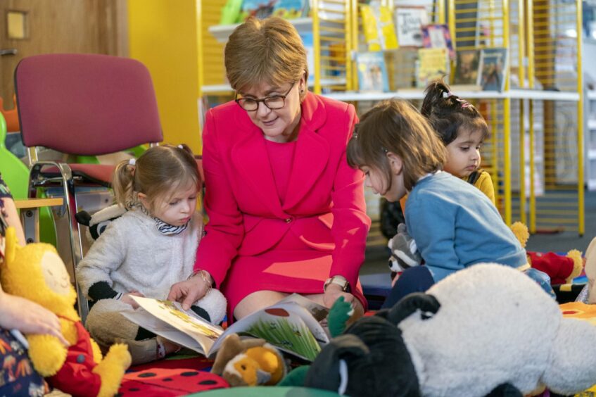 Nicola Sturgeon reads a book to young girls in pyjamas