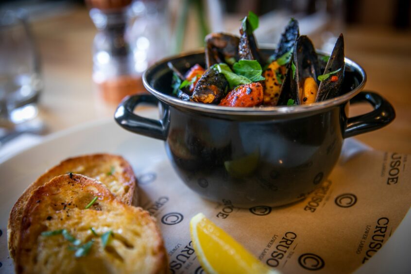 A pot of mussels with a side of garlic bread in The Crusoe.