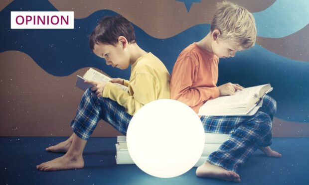 two boys in pyjamas reading books.