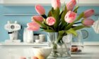 A bunch of flowers in a kitchen with a cup of tea. This gives you an idea of some spring decoration ideas!