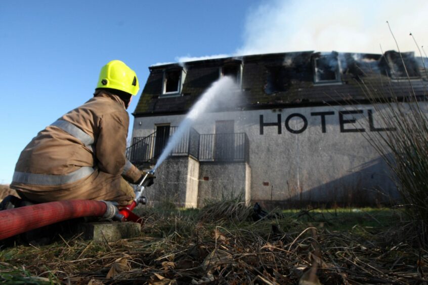 Fire fighter firing water hose at Hotel building