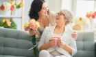 Mother and daughter celebrating Mother's Day with flowers and a gift.