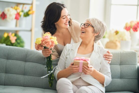 Mother and daughter celebrating Mother's Day with flowers and a gift.
