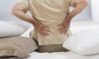 Man suffering from back pain getting out of bed before seeking back pain treatment in Perth