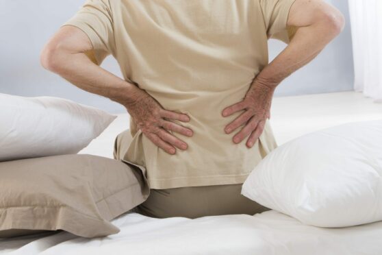 Man suffering from back pain getting out of bed before seeking back pain treatment in Perth