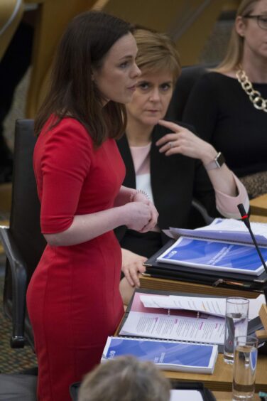 Kate Forbes in the Scottish Parliament, watched by a serious faced Nicola Sturgeon.