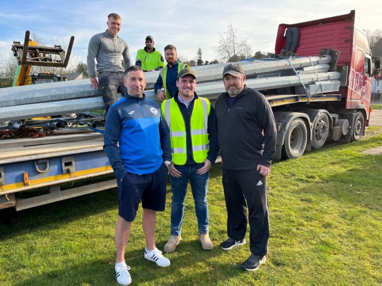 Martin Glen of Fair City Kids and Kinnoull groundsman Kevin Graham flank Kilmac contracts manager Greg Hutcheson, with Kilmac trio Ryan Wann, Jamie Smyth and Lawrence O’Brien set to unload hefty lighting columns at Tulloch Park.