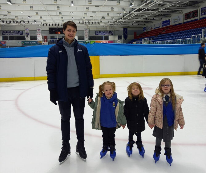 A photo of a pro skater with three school pupils on Learn to Skate at Dundee ice arena.