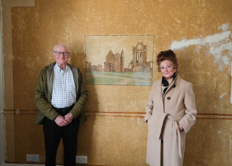 Brother and sister John and Nancy pose in front of Arbroath Abbey painting by their dad.